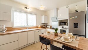 Eine moderne Küche mit weißen Schränken, einer Holz Arbeitsplatte, einem eingebauten Geschirrspüler, einer Mikrowelle, einem Herd und einem Kühlschrank.