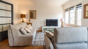 Ein modernes Wohnzimmer mit einer Couch, einem Fernseher und einem Fenster mit Jalousien.