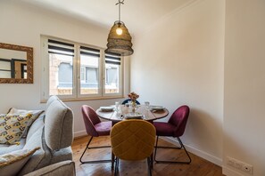 A dining area with a round table, two chairs, and a hanging light fixture. - Le Roz Cocoon - Hypercentre à 10mn de la plage (Perros-Guirec)