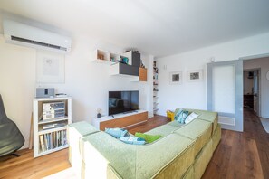 Un salon moderne avec un téléviseur à écran plat, un canapé, une bibliothèque et un coin repas.