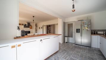 A modern kitchen with white cabinetry, a central island, and a stainless steel refrigerator.