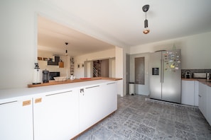 Une cuisine moderne avec des meubles blancs, un îlot central et un réfrigérateur en acier inoxydable.
