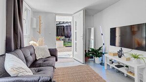 A modern living room with a grey sofa, a flat-screen TV, and a white entertainment unit.