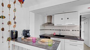 A modern kitchen with white cabinets, a stainless steel range hood, and a black countertop.