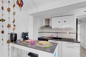 A modern kitchen with white cabinets, a stainless steel range hood, and a black countertop.