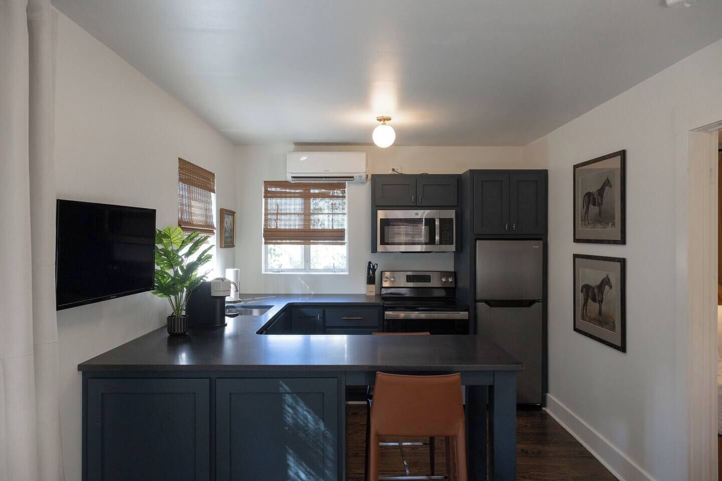 A modern kitchen with a flat-screen TV, built-in microwave, oven, and refrigerator.