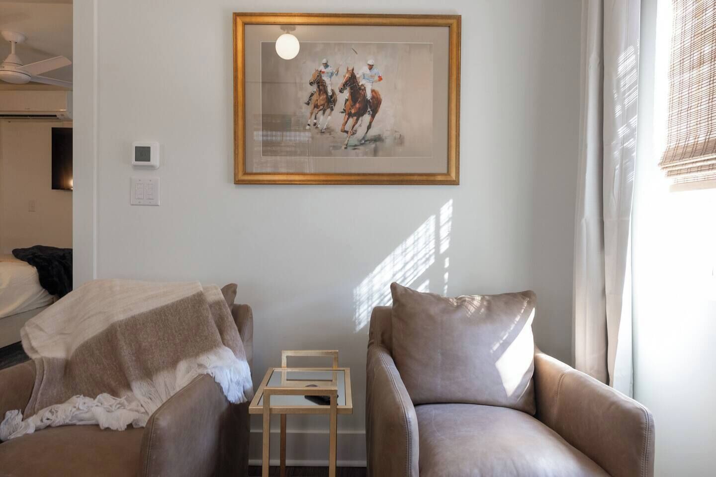 Habitación de hotel con una cama, dos sillones, una mesita y un cuadro en la pared.