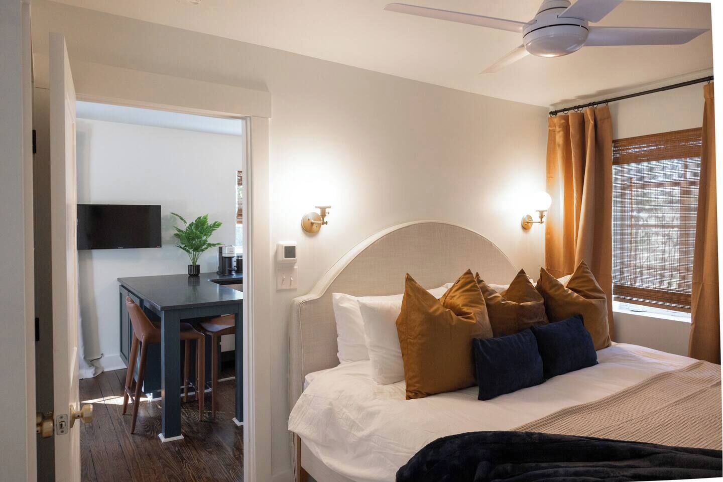 Una habitación de hotel con cama, escritorio, televisor y ventilador de techo.