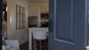 Una cocina moderna con armarios blancos, un microondas y un taburete de bar.