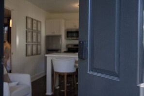 A modern kitchen with white cabinetry, a microwave, and a bar stool.
