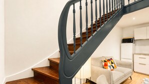 Eine Treppe mit Holzboden und schwarzen Geländern, die zu einer Zwischenebene führt.