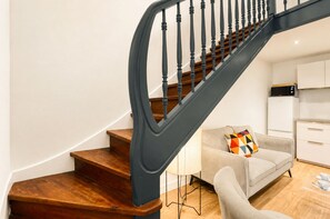 Eine Treppe mit Holzboden und schwarzen Geländern, die zu einer Zwischenebene führt.