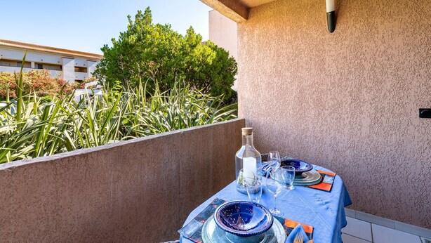 A table set for dining with a blue tablecloth, plates, glasses, and a bottle. - La Plage d'Irène (Appartement n°36) - Avec balcon (San-Nicolao)