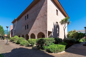 A building with a distinct architectural style, featuring a prominent corner tower and a series of arches along the facade. - La Plage d'Irène (Appartement n°36) - Avec balcon (San-Nicolao)