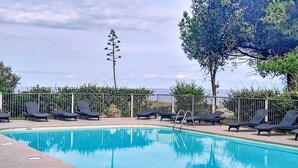 A swimming pool with lounge chairs and a view of the sea. - La Plage d'Irène (Appartement n°36) - Avec balcon (San-Nicolao)