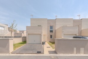 A modern residential building with a garage, a small driveway, and a clear sky. - Le Cocon des Yvelines - Jolie maison avec jardin (Aubergenville)