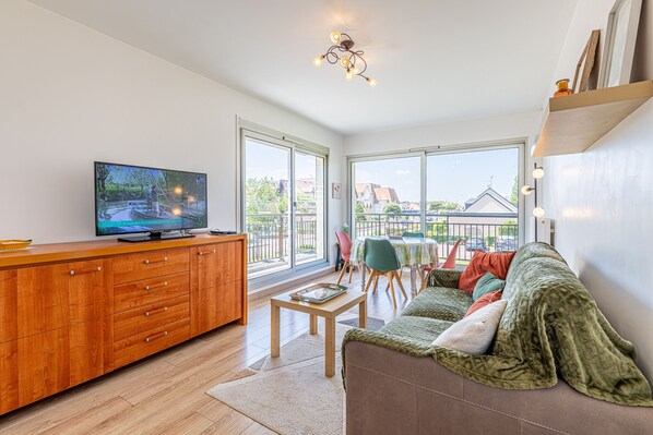 Una sala de estar moderna con televisor, mueble de madera, sofá y un balcón con vistas.