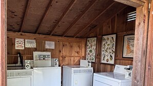 A laundry room with three white washing machines, wooden walls, and a wooden ceiling. - 3-bedroom campground in delightful Covington with AC comfort (Covington)
