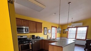 A kitchen with wooden cabinets, stainless steel appliances, and a central island. - 3-bedroom campground in delightful Covington with AC comfort (Covington)