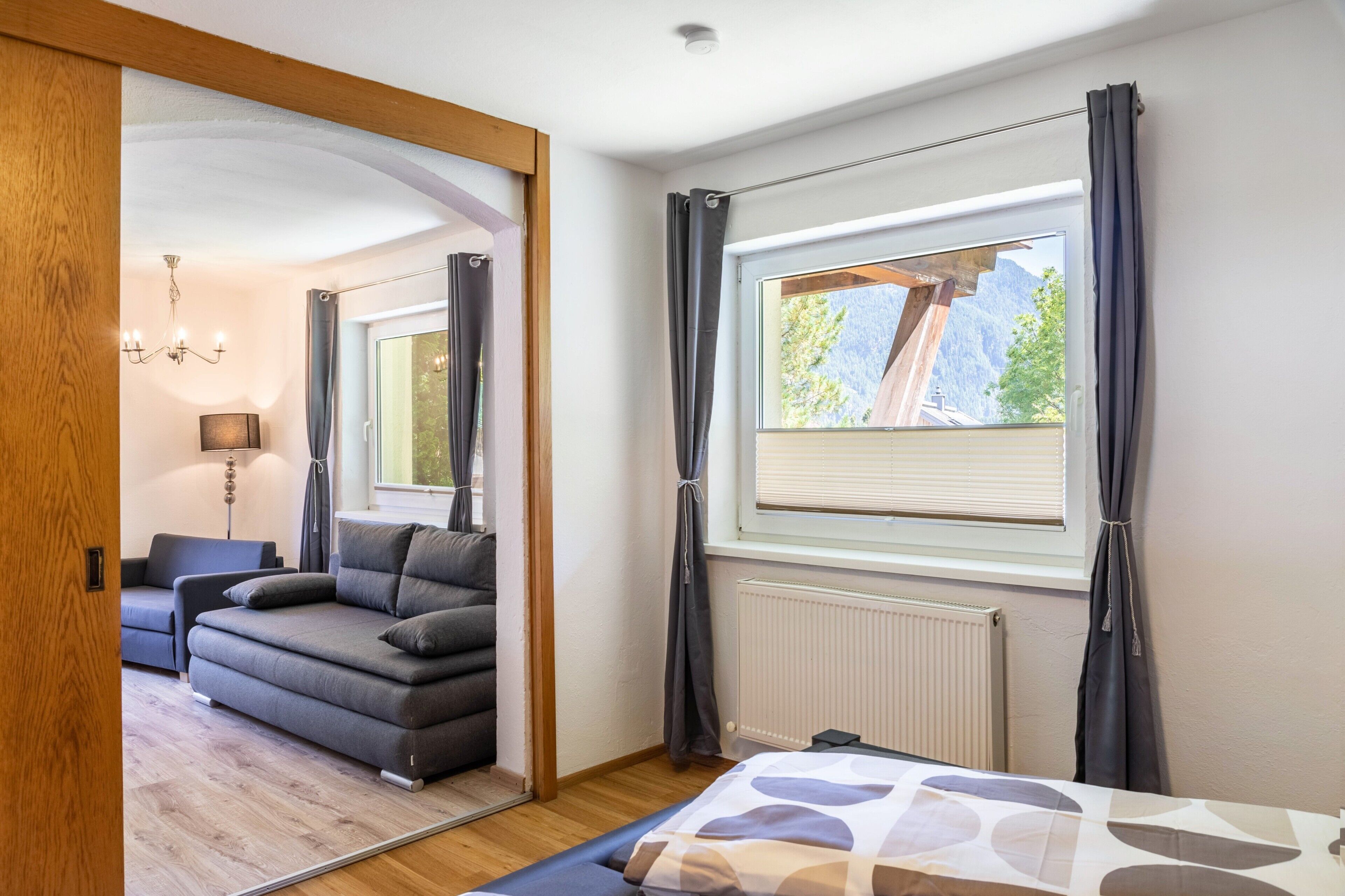 A modern bedroom with a large window, a radiator, and a sofa.