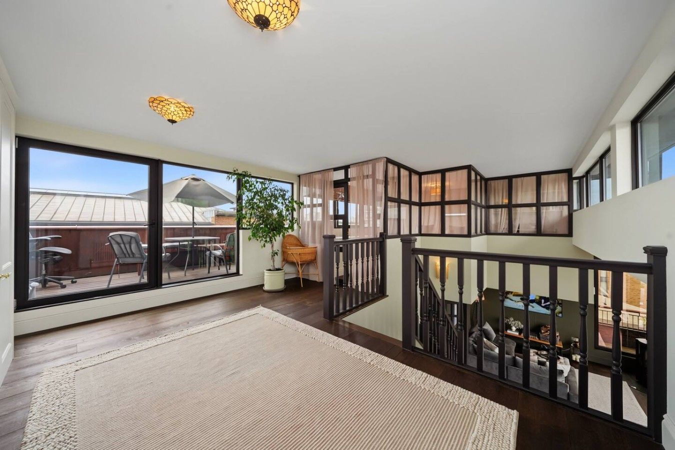 A spacious room with a large window, a staircase, and a view of the outdoors.