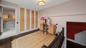 Una camera da letto con un letto, una scrivania, una sedia, un comò, uno specchio e una lampada a soffitto.