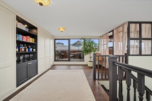 Ein Flur mit Bücherregal, einer Treppe und Blick auf eine Außenpatio-Terrasse.
