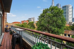 A balcony with a wooden floor, metal railing, and outdoor furniture including a table and chairs. - Skyline terraces & double-height living near Borough Market (London)