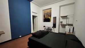 A bedroom with a bed, a chair, a table, a lamp, and a poster on the wall. - APARTMENT IN BOGOTÁ'S HISTORIC CENTER (Bogotá, D.C.)