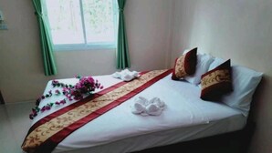A hotel room with a bed, green curtains, and a floral arrangement.