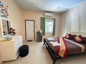 Habitación de hotel con cama, escritorio, espejo, cesto de basura y ventana con cortinas.