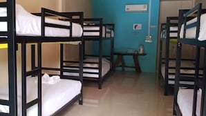 Ein Zimmer mit Etagenbetten, einem kleinen Tisch und einer Wand-Klimaanlage.