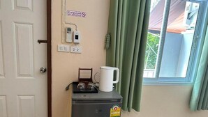 Eine kompakte Küchenzeile mit Kaffeemaschine, kleinem Kühlschrank und Steckdose.