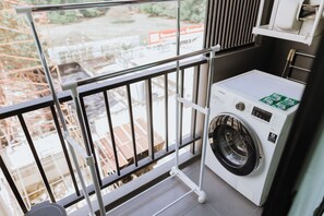 A balcony with a metal railing, a washing machine, and a view of a construction site. - 701 Cozy 1-bedroom Condo in Nimman - 4 mins walk to Maya Mall and One Nimman (Chang Wat Chiang Mai)