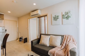 Ein Wohnzimmer mit einer Couch, einem Sessel, einer Klimaanlage und zwei Wandbildern.