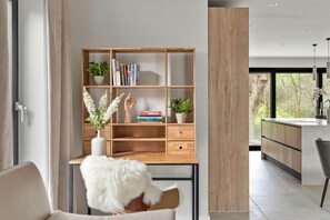 A modern living space with a wooden desk, books, plants, and a white fluffy chair. - Stunning Bude Retreat With Hot Tub (Bude)