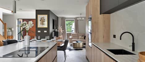 A modern kitchen with a central island, wooden cabinetry, and a large window.
