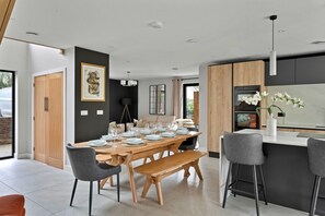 Une cuisine moderne avec une table à manger en bois pour quatre personnes, un coin bar et une grande fenêtre laissant entrer la lumière naturelle.