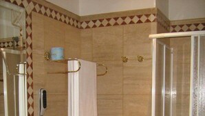 Een badkamer met een wastafel, spiegel, handdoekhouder, douche en toilet.