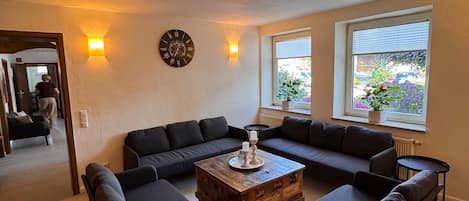 A living room with a sectional sofa, a coffee table, and a wall clock.
