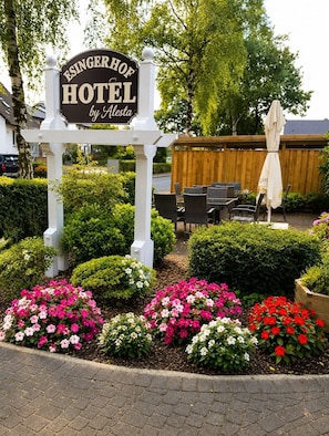 A sign for the Esingerhof Hotel by Flessa, surrounded by well-maintained flower beds and outdoor seating. - Hotel Esingerhof by Alesta (Tornesch)