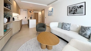 Ein modernes Wohnzimmer mit einer Couch, Sesseln, einem Couchtisch und einem Essbereich mit einer Bar.