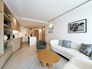 Ein modernes Wohnzimmer mit einer Couch, Sesseln, einem Couchtisch und einem Essbereich mit einer Bar.