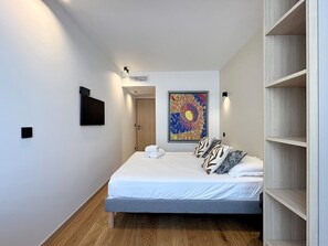 Ein Schlafzimmer mit einem Bett, einem Bild, einem Kleiderschrank und einer Tür.