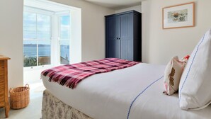 Un dormitorio con cama, armario, ventana con vistas y un cuadro en la pared.