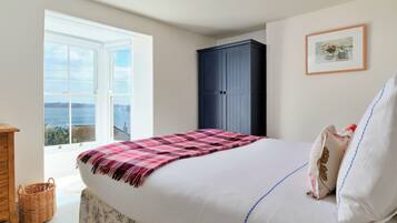 Un dormitorio con cama, armario, ventana con vistas y un cuadro en la pared.