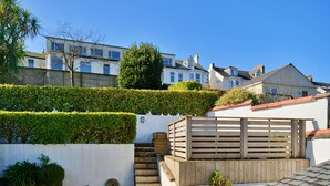 Una zona residencial con una casa blanca, una valla de madera y un cielo azul despejado.