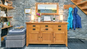 Eine Holzkommode mit Schubladen, ein Spiegel darüber und eine Steinwand im Hintergrund.