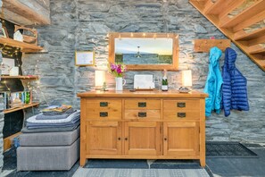 A wooden dresser with drawers, a mirror above it, and a stone wall behind. - Charming Snowdonia Slate Cottage (Blaenau Ffestiniog)