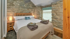 Ein Schlafzimmer mit einer Steinsäule, einem hölzernen Bettgestell, einem Nachttisch, einer Lampe und einem Fenster mit Blick.